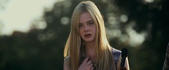 Movie still from “Super 8” (2011), directed by J.J. Abrams – A girl with long blonde hair is posing for a picture; Close Up shot, Over the shoulder angle