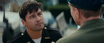 Movie still from “Super 8” (2011), directed by J.J. Abrams – A man in a police uniform talking to another man; Close Up shot, Over the shoulder angle
