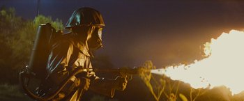 Movie still from “Super 8” (2011), directed by J.J. Abrams – A man in a helmet and a gas mask is holding a fire hose; Medium shot, Low angle