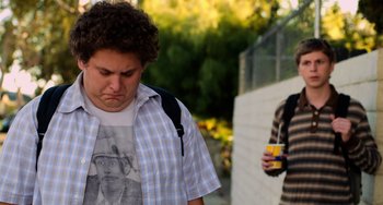 Movie still from “Superbad” (2007), directed by Greg Mottola – A young man is standing outside with his hands on his hips; Medium shot, Over the shoulder angle