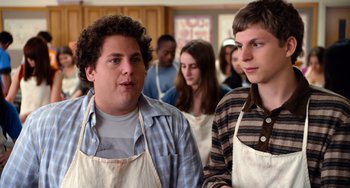 Movie still from “Superbad” (2007), directed by Greg Mottola – Two men in aprons standing next to each other in a kitchen; Medium shot, Over the shoulder angle