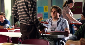 Movie still from “Superbad” (2007), directed by Greg Mottola – A man sitting at a table in front of another man; Medium shot, Over the shoulder angle