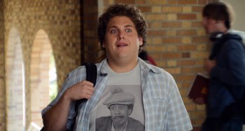 Movie still from “Superbad” (2007), directed by Greg Mottola – A man in a plaid shirt and a hat is holding a backpack; Close Up shot, Over the shoulder angle