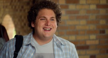 Movie still from “Superbad” (2007), directed by Greg Mottola – A person with curly hair smiling; Close Up shot, Over the shoulder angle