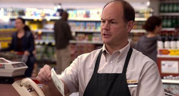 Movie still from “Superbad” (2007), directed by Greg Mottola – A man in an apron is holding money in a store; Medium shot, Low angle