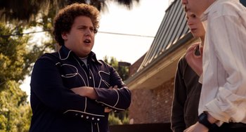 Movie still from “Superbad” (2007), directed by Greg Mottola – Two men standing next to each other in front of a building; Medium shot, Over the shoulder angle