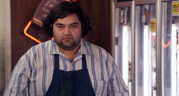 Movie still from “Superbad” (2007), directed by Greg Mottola – A man in a striped shirt and an apron; Medium shot, Over the shoulder angle