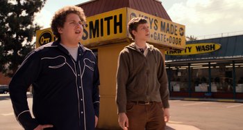 Movie still from “Superbad” (2007), directed by Greg Mottola – Two young men standing in front of a store front; Medium shot, Low angle