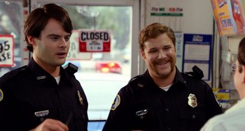 Movie still from “Superbad” (2007), directed by Greg Mottola – Two police officers standing next to each other in front of a closed sign; Close Up shot, Over the shoulder angle