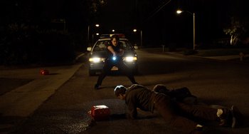 Movie still from “Superbad” (2007), directed by Greg Mottola – A police officer is on the ground near a woman in the street; Wide shot, Low angle