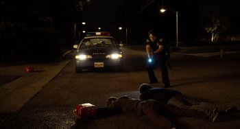 Movie still from “Superbad” (2007), directed by Greg Mottola – A police officer is investigating a body on the street; Wide shot, Low angle
