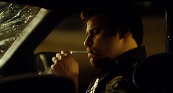 Movie still from “Superbad” (2007), directed by Greg Mottola – A police officer smoking a cigarette while sitting in a car; Close Up shot, Over the shoulder angle
