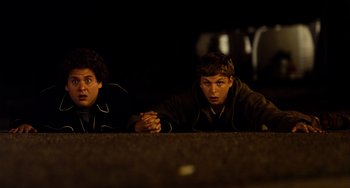 Movie still from “Superbad” (2007), directed by Greg Mottola – Two young men sitting next to each other on the ground; Medium shot, High angle