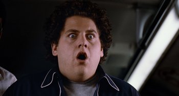 Movie still from “Superbad” (2007), directed by Greg Mottola – A person with curly hair looking surprised; Close Up shot, Low angle