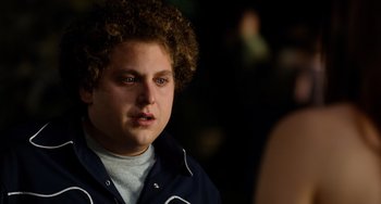 Movie still from “Superbad” (2007), directed by Greg Mottola – A young man with curly brown hair and blue eyes; Close Up shot, Over the shoulder angle
