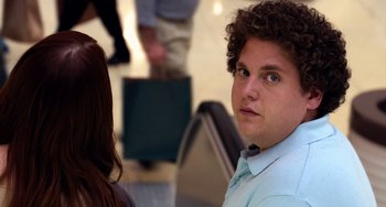 Movie still from “Superbad” (2007), directed by Greg Mottola – A young man with blue eyes and curly hair looking into the camera; Close Up shot, Over the shoulder angle