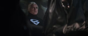 Movie still from “Superman” (1978), directed by Richard Donner – A man in a black superman costume; Medium shot, Over the shoulder angle
