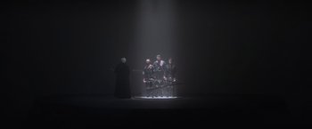 Movie still from “Superman” (1978), directed by Richard Donner – A group of people standing on a stage in a dark room; Wide shot, Low angle