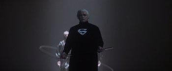 Movie still from “Superman” (1978), directed by Richard Donner – A man dressed as superman holding a pair of sticks; Medium shot, Low angle