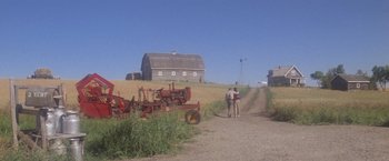 Movie still from “Superman” (1978), directed by Richard Donner – Two people are walking down a dirt road near farm equipment; Extreme Wide shot, High angle