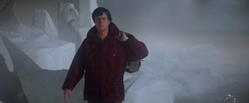 Movie still from “Superman” (1978), directed by Richard Donner – A man in a red plaid jacket holding a backpack; Medium shot, Low angle