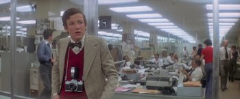 Movie still from “Superman” (1978), directed by Richard Donner – A young man holding a camera in an office setting; Close Up shot, Low angle