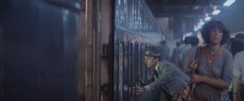 Movie still from “Superman” (1978), directed by Richard Donner – A man leaning against a metal fence; Medium shot, Low angle