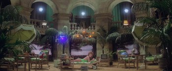 Movie still from “Superman” (1978), directed by Richard Donner – A woman in a green bathing suit laying on a lounge chair; Extreme Wide shot, High angle