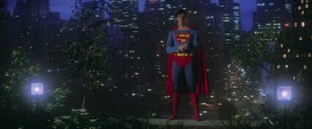 Movie still from “Superman” (1978), directed by Richard Donner – A man dressed as superman standing in front of a city skyline at night; Wide shot, Low angle
