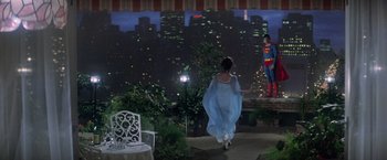 Movie still from “Superman” (1978), directed by Richard Donner – A woman in a blue dress walking down a sidewalk; Wide shot, Over the shoulder angle