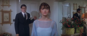 Movie still from “Superman” (1978), directed by Richard Donner – A woman in a white dress standing next to a man; Medium shot, Over the shoulder angle