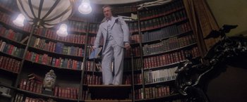 Movie still from “Superman” (1978), directed by Richard Donner – A man in a suit standing in front of a book shelf; Wide shot, Low angle