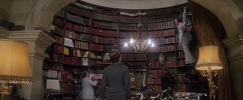 Movie still from “Superman” (1978), directed by Richard Donner – Two women are standing in front of a library full of books; Wide shot, Low angle