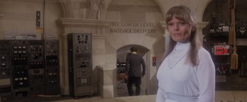 Movie still from “Superman” (1978), directed by Richard Donner – A woman standing in front of an entrance to an airport; Medium shot, Low angle