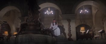 Movie still from “Superman” (1978), directed by Richard Donner – A woman in a white dress sitting on a staircase; Wide shot, Low angle