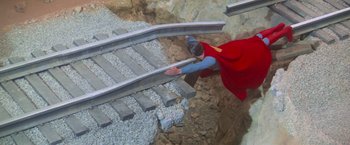 Movie still from “Superman” (1978), directed by Richard Donner – A woman in a red cape is climbing up a train track; Medium shot, High angle