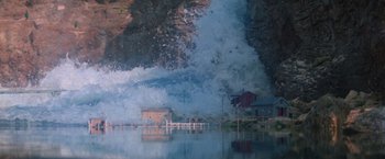 Movie still from “Superman” (1978), directed by Richard Donner – A large wave crashing into a house and a pier; Extreme Wide shot, High angle