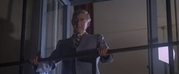 Movie still from “Superman” (1978), directed by Richard Donner – An older man in a suit holding a baseball bat; Medium shot, Low angle