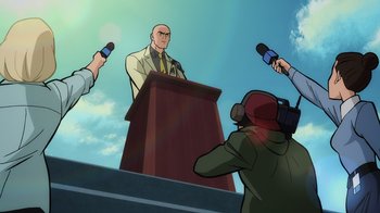 Movie still from “Superman: Man of Tomorrow” (2020), directed by Chris Palmer – A man is speaking at a podium in front of a group of reporters; Medium shot, Low angle