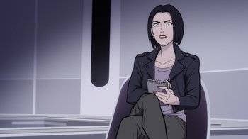 Movie still from “Superman: Man of Tomorrow” (2020), directed by Chris Palmer – A woman sitting on a chair holding a notebook; Medium shot, Over the shoulder angle