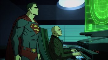 Movie still from “Superman: Man of Tomorrow” (2020), directed by Chris Palmer – A man sitting at a computer next to a man standing next to him; Medium shot, Over the shoulder angle