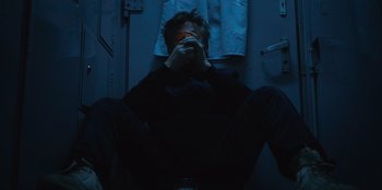 Movie still from “Superpower” (2023), directed by Aaron Kaufman – A man sitting on the floor with his eyes closed; Medium shot, Overhead angle