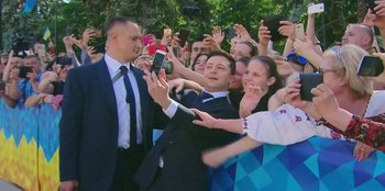 Movie still from “Superpower” (2023), directed by Aaron Kaufman – A group of people taking pictures with a man holding a cell phone; Medium shot, Low angle