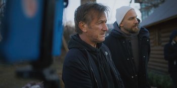 Movie still from “Superpower” (2023), directed by Aaron Kaufman – A man in a black jacket and a man in a white hat; Medium shot, Over the shoulder angle