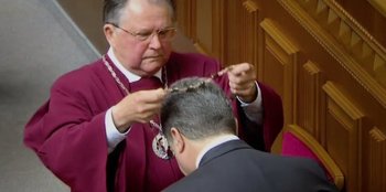 Movie still from “Superpower” (2023), directed by Aaron Kaufman – A man in a red robe is fixing a man's hair; Close Up shot, Low angle