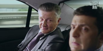 Movie still from “Superpower” (2023), directed by Aaron Kaufman – A man sitting in the back seat of a car; Close Up shot, Over the shoulder angle