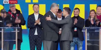 Movie still from “Superpower” (2023), directed by Aaron Kaufman – Two men in suits shaking hands in front of a group of people; Wide shot, Low angle