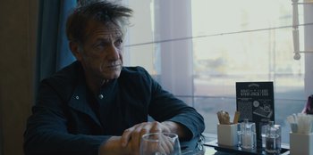 Movie still from “Superpower” (2023), directed by Aaron Kaufman – A man sitting in front of a window at a table; Close Up shot, Over the shoulder angle