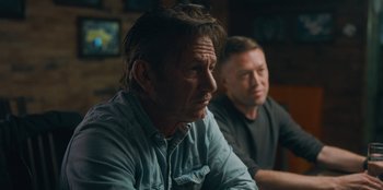 Movie still from “Superpower” (2023), directed by Aaron Kaufman – Two men sitting at a table in front of a television; Close Up shot, Over the shoulder angle