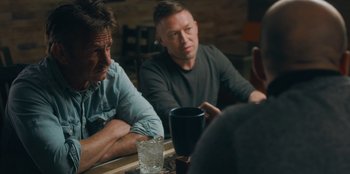 Movie still from “Superpower” (2023), directed by Aaron Kaufman – A group of men sitting at a table with drinks; Medium shot, Over the shoulder angle